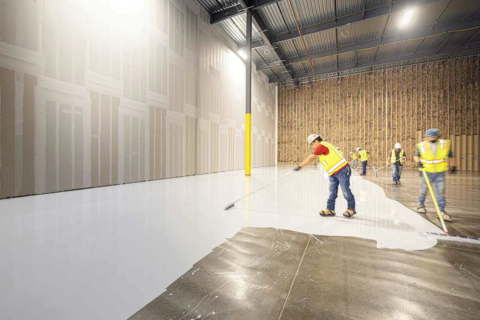 Crew applying a white coating in a large warehouse